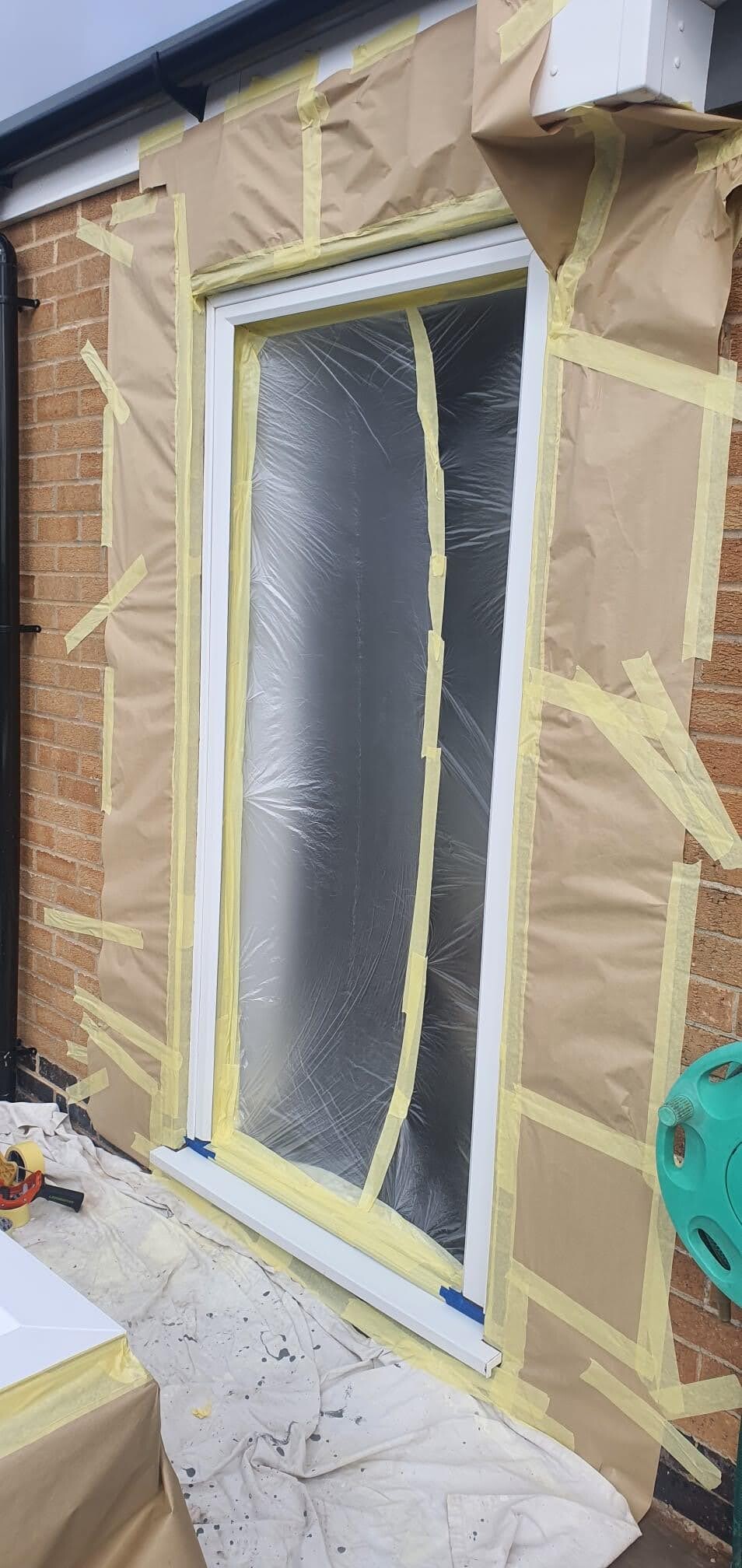 Door surround and adjacent brickwork masked before spraying